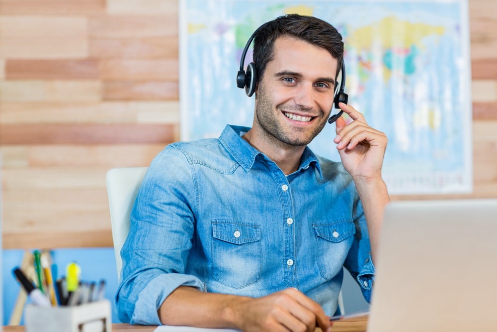 Handsome travel agent smiling at camera in the office Handsome travel agent smiling at camera in the office